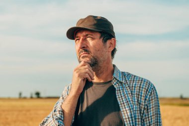 Olgun buğday tarlasında duran erkek çiftçinin portresi.