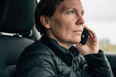 Serious female driver talking on mobile phone from the car, selective focus clipart