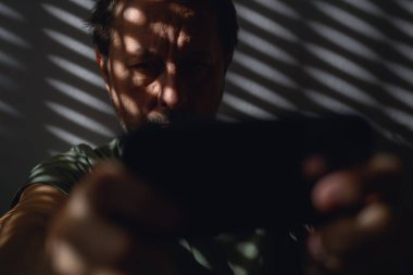 Karanlık odada akıllı telefondan video oyunu oynayan adamın seçmeli odağı