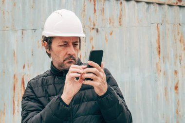 İnşaat mühendisi inşaat alanında akıllı telefon kullanıyor, seçici odaklı.