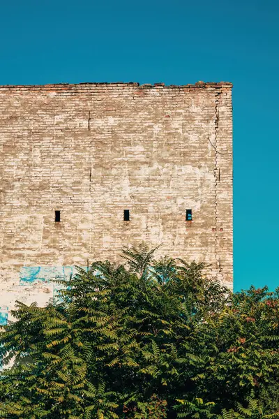 Açık mavi gökyüzünün altındaki eski harap tuğla duvar, seçici odak