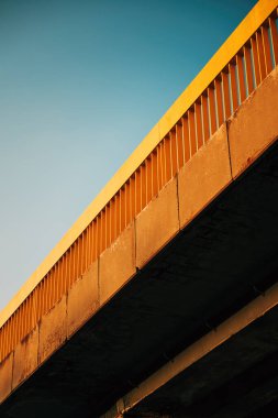 Sarı metal çitli eski aşınmış beton köprünün düşük açılı görüntüsü, seçici odaklı.