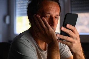 Sıkıcı, olgun bir adam cep telefonuna bakıyor, seçici odaklanıyor.