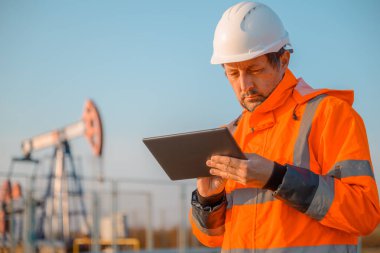 Petrol ve gaz sürecini denetlerken dijital tablet bilgisayar kullanan sondaj sondajı mühendisi, alanda sondaj performansını izleme, seçici odaklanma