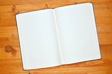 Ofis masasında bir defter, boş beyaz sayfalı bir günlük, metin modeli, üst görünüm