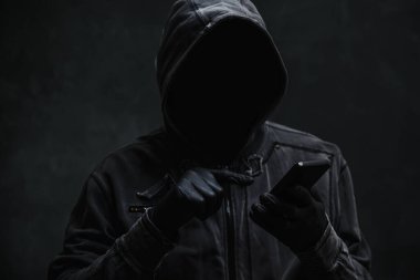 Kapüşonlu bilgisayar korsanı akıllı telefon kullanıyor, seçici odaklanma