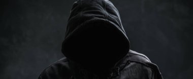 Tanımlanamayan siber suçlu veya siyah kapüşonlu ceket giyen bilgisayar korsanı, sade bir portre, seçici bir odak noktası.