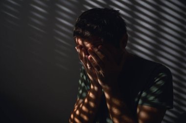 Zihinsel sağlık farkındalık ayı konsepti, karanlık odada ağlayan yetişkin erkek imajı, seçici odaklanma.