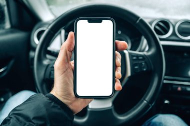 Akıllı telefon model ekranı, soğuk kış gününde arabada cep telefonu kullanan erkek sürücü, seçici odaklanma