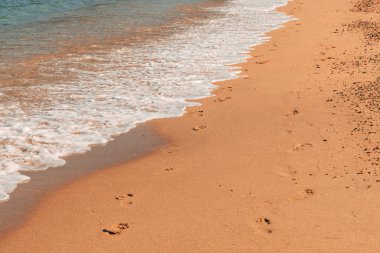 Deniz köpüğü yaz mevsiminde ıslak kumsalda insan ayak izlerini yıkıyor, tatil ve deniz arka planında tatil, seçici odaklanma