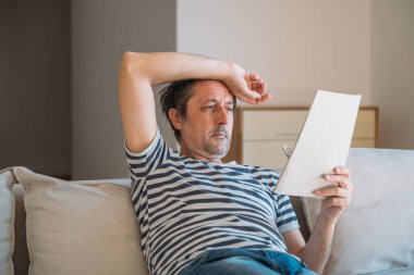 Adam evde kullanma kılavuzu kağıdı okuyor, seçici odaklanma