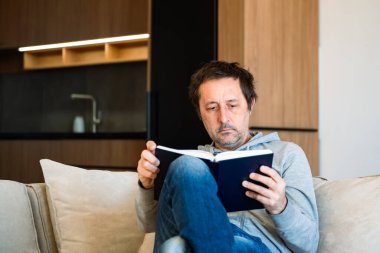 Ömür boyu öğrenme konsepti, sabahları evde kitap okuyan adam, seçici bir odaklanma.