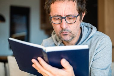 Ömür boyu öğrenme konsepti, sabahları evde kitap okuyan adam, seçici bir odaklanma.