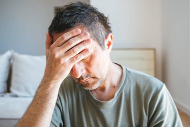 Oturma odasında üzgün ve depresif bir adamın portresi, evde yalnız, seçici bir odaklanma.