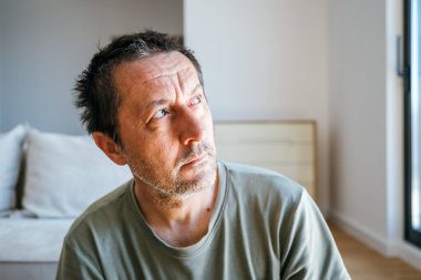 Düşünceli bir adamın portresi sabah oturma odasında oturuyor, düşünüyor ve pencereden dışarı bakıyor, seçici bir odak noktası.