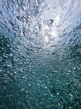 Su altı hava kabarcıkları temiz mavi okyanus suyunda doğal arka plan olarak, düşük açı görüntüsü, seçici odaklanma