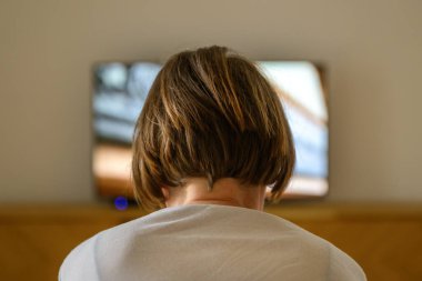 Kanepede oturan ve oturma odasında televizyon izleyen, seçici odaklı kadın görüntüsü.