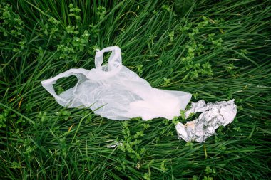 Çöp ve çevresel hasar, plastik torba ve yeşil çimlerin üzerindeki çöp, üst görünüm
