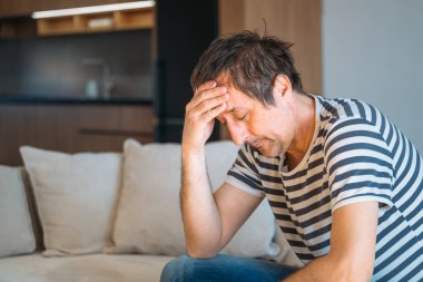 Evde üzgün, hayal kırıklığına uğramış bir adam, zihinsel sağlık ve depresyon konsepti, seçici odaklanma