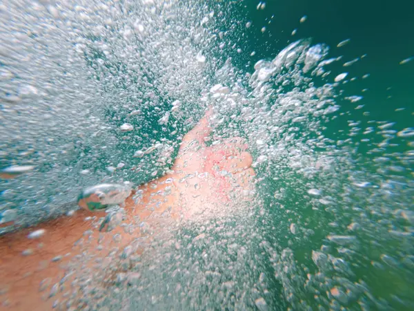 Açık deniz suyunda el kol hareketi yapan adam onaylama ve onaylama işareti olarak seçici bir odak noktası.