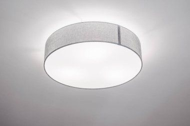 Sığ davul gölgeli tavan lambası. Gri pamuk ayırıcı, zarif, minimalist iç mekan, seçici odak.