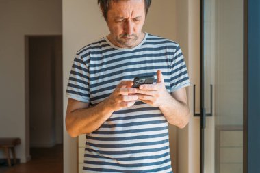 Evdeki cam balkon kapısının yanında cep telefonu kullanan adam, seçici odaklı.