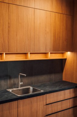 Su musluğu ve metalik lavabo modern parlak mutfakta kurşun şeritli ışık, seçici odak