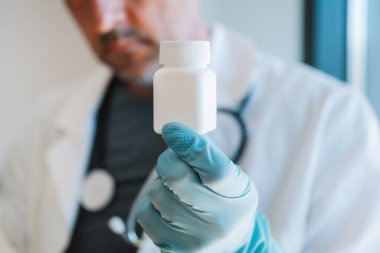 Eczacının elinde eczanede plastik bir ilaç şişesi var, seçici odaklı.