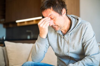 Sabah yorgunluğu, uykulu yorgun adam oturma odasındaki kanepede oturuyor, seçici bir şekilde odaklanıyor.