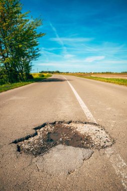 Asfalt yol yüzeyinde büyük bir çukur, köy yolunda bir delik, seçici odak