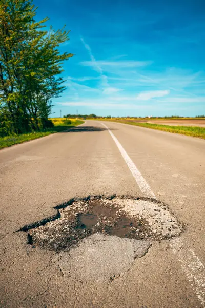 Asfalt yol yüzeyinde büyük bir çukur, köy yolunda bir delik, seçici odak
