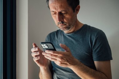 Aşırı akıllı telefon kullanımı, evde cep telefonu kullanan adam, seçici odaklanma