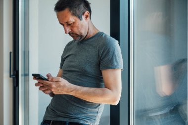 Aşırı akıllı telefon kullanımı, evde cep telefonu kullanan adam, seçici odaklanma