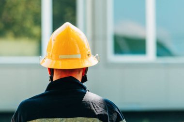 Sarı koruyucu kasklı, seçici odaklı erkek itfaiyecinin arka görüntüsü.