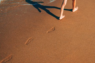 Yazın okyanusa yakın ıslak kumsalda çocuğun ayakları seçici bir odak noktası.