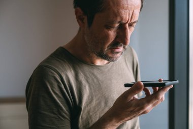 Telefonu suratının önünde tutmak ve konuşmak, adam cep telefonuyla konuşurken aleti ağızdan uzak tutmak, seçici odaklanma.