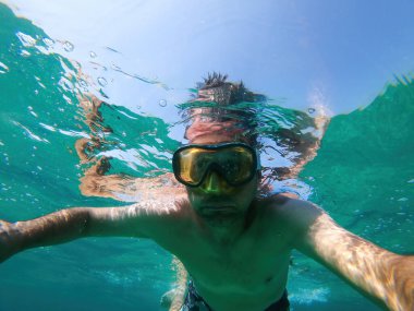 Dalgıç maskeli bir adam yaz tatilinin tadını çıkartıyor. Denizde, seçici bir odaklanma ile sualtı çekimi.