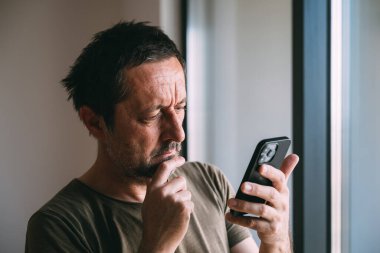 Cep telefonundan kötü haber mesajı okuyan adam, seçici odaklanma