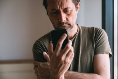 Cep telefonundan kötü haber mesajı okuyan adam, seçici odaklanma