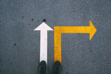 Asfaltta beyaz ve sarı oklar farklı yönleri gösteriyor. Yoldaki boyanmış oklar seçim ve yönü simgeliyor. Üst görünüm.