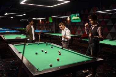 Bir grup mutlu arkadaş bilardo oynuyor, bilardoda oynayan yakışıklı genç bir adam var.