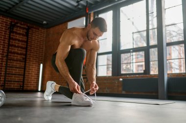 Spor ayakkabılarını bağlayan sporcunun spor salonunda antrenman yapmaya hazırlanması. Fitness ve vücut geliştirme konsepti