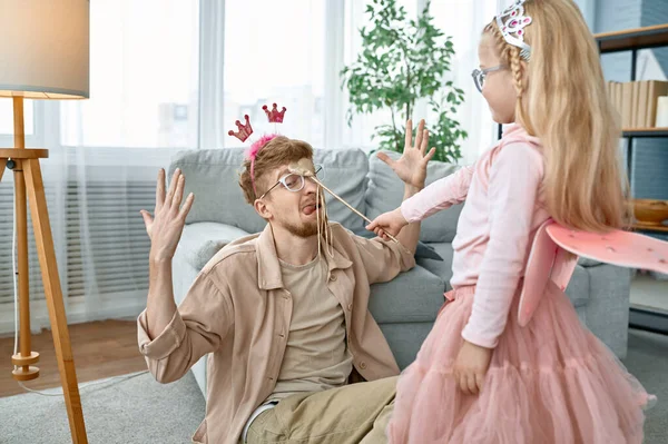 可爱的小女儿公主带着魔杖 父亲穿着戏服在家里开玩笑 — 图库照片