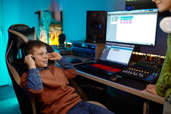 在录音室里的孩子们 十几岁的男孩坐在桌子旁 带着音响制作设备 听着新的配乐 — 图库照片