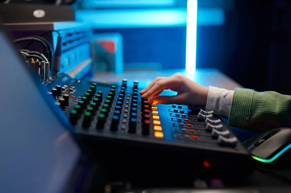 Side view closeup audio engineer hand on sound mixer control panel inside production house