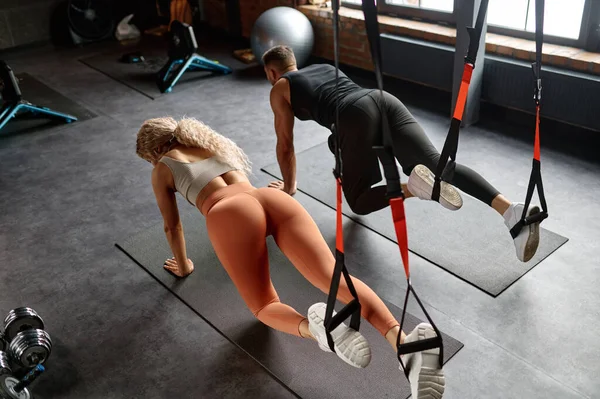 陸上競技の男の女性はTrx機器を使用してクロスフィットトレーニングを行います 若い女性と男性が混乱に足を入れて オーバーヘッドビュー — ストック写真