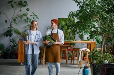 Yaratıcı sanat stüdyosunda iki profesyonel çiçek sanatçısı. Yaratıcı kompozisyon için elinde çiçekler ve yosun tutan mutlu genç adam ve kadın. Çiçek, el yapımı ve küçük işletme konsepti