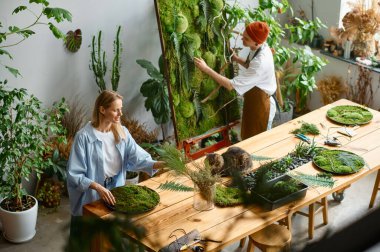 Çiçekçi ve dekoratör yukarıdaki bitkilerden el işi çiziyor. Yaratıcı tasarımcı mesleği