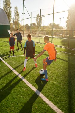 Çocuklar için antrenman kampında futbol oynayan genç çocuklar. Yaz gününde gençler için spor turnuvası