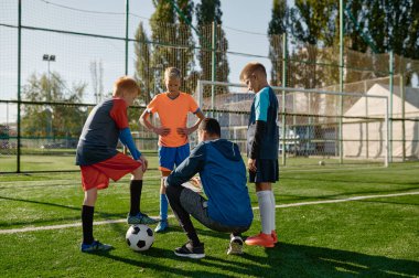 Futbol koçu, genç futbolcularla stratejileri gözden geçiriyor. Okul çimlerinde maç öncesi futbol antrenmanı